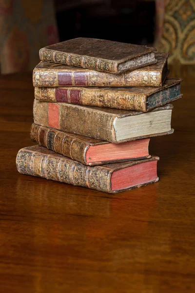 Pile of antique books with a leather cover and golden ornaments on a wooden table