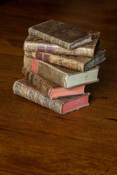 Куча старинных книг с кожаным чехлом и золотыми орнаментами на деревянном столе