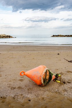 İtalya 'da Emilia Romagna' da Cattolica sahilinde bir turuncu şamandıra. Kışın bulutlu bir gökyüzünün altında..
