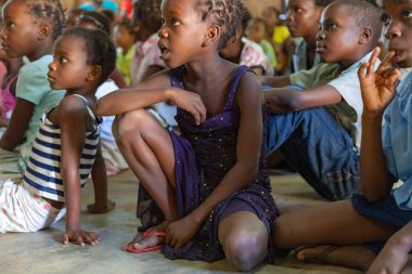 Close up front view of African children in the congregaton of Pentecostal Christian Sunday church service eyes open listening actively to the pastor and the preacher guests. Pentecostal worship with families metaphor for hope, redemption and salvatio clipart