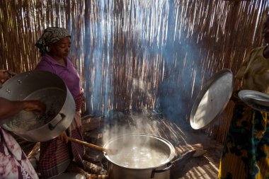 Xai Xai Mozambik: Kadınlar kaba bir mutfakta, hayır işçileri ve çocuklar için bir tarlada sopa duvarları olan yemekleri otantik ve geleneksel yollarla hazırlıyorlar.