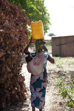Xai Xai Mozambik: Kadınlar kovalarla su topluyor ve capulana veya bebek taşıyıcısı veya yanlarında yürüyen bir çocukla başlarının üzerinde taşıyorlar.