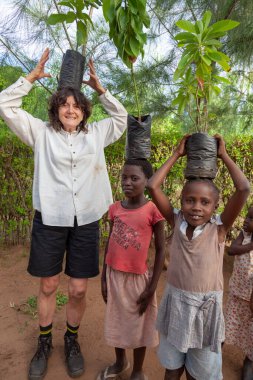 Xai Xai, Mozambik - Nisan 2014: Bir Avustralyalı misyonere fidanlıktan ekme sahasına genç ağaçları nasıl taşıyacağını öğreten genç kızlar.