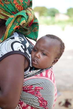 Geleneksel giysi ve bebek taşıma metodlarını gösteren kapuçinalı bebekli kimliği belirsiz kadının portresini yakın plan çekin..
