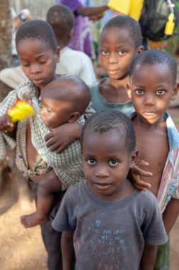 Xai Xai, Mozambik, Nisan 2014: Fakir bir köyde görev yapan Avustralyalı bir çocuğun portresini yaptırmak isteyen genç çocukların grup fotoğrafı. Küçük kardeşi sakinleştirmek için bebek çıngırağı kullanan bir çocuk..