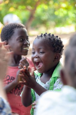 Xai Xai, Mozambik, Nisan 2014: Çocuklar için oyun zamanı - fakir bir köydeki Avustralyalı misyoner işçilerden yeni bir el çırpma oyunu öğrenen örgülü küçük kız. Yoksulluktan umut