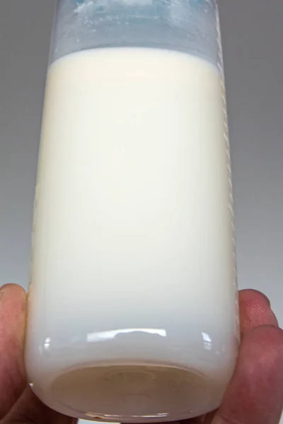 表达母乳的样本显示 母乳密度在一个可供食用的瓶子中 底部是淡牛奶 顶部是奶油 婴儿奶瓶由人类手拿着 用于施胶 — 图库照片