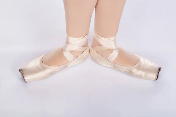 En Pointe CORRECT First position open from above dancers perspective Close up of young female ballet dancer showing various classic ballet feet positions for classical ballet or dance against a white background in pink silk and satin pointe shoes