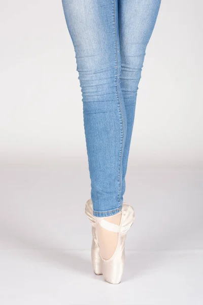 En Pointe CORRECT Fifth position with blue jeans front on teachers perspective Young female ballet dancer showing various classic ballet feet positions for classical ballet or dance against a white background in blue jeans pink silk and satin pointe