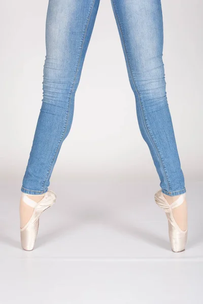 En Pointe CORRECT second position with blue jeans front on teachers perspective Young female ballet dancer showing various classic ballet feet positions for classical ballet or dance against a white background in blue jeans pink silk and satin pointe