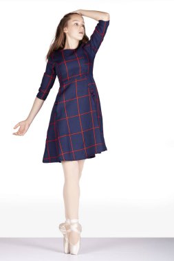 En Pointe 'in ilk pozisyonu, sağ el üstünde yürümek, hayal kırıklığını, öfkeyi ifade etmek için metafor ya da sembol, beyaz arka plan tartan elbisesi ve saten puanlı ayakkabılar giyen genç bayan bale dansçısı.
