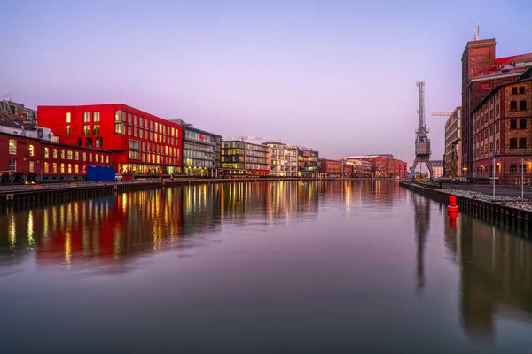 Günbatımında Munster 'da vinçli sanayi ve iş binaları olan şehir limanı.