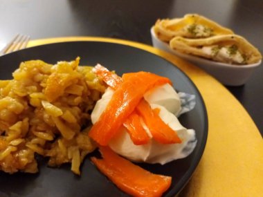 Fried grated potatoes with sour cream, salmon and naan bread on a black plate