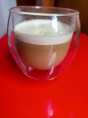 Hot coffee in a glass on a red table