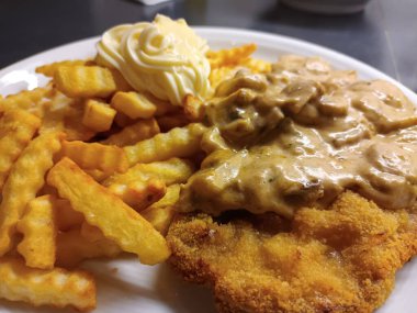 Mantar soslu, kızarmış patates ve mayonezli Viyana şnitzeli.