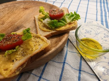 Domatesli tost, salata, sos ve zeytinyağlı bir bardak.