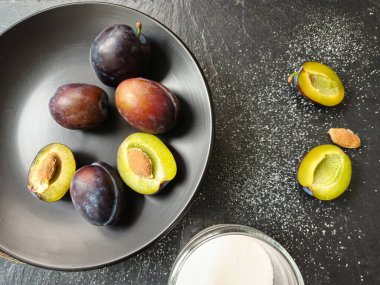 Siyah bir tabakta erikler ve şeker kavanozu