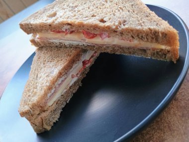 Bir tabakta jambon ve peynirli sandviç.