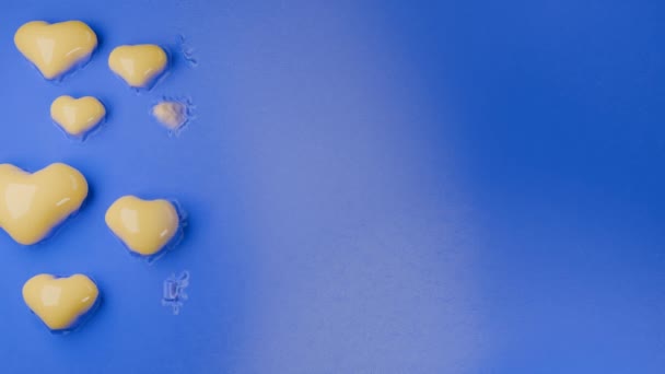 黄色い心臓が膨張する青い表面の3Dアニメーション バレンタインデーのアニメーション 抽象的な背景 — ストック動画