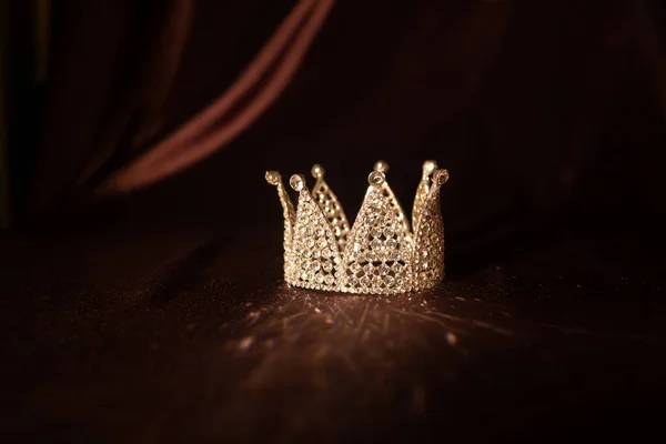 茶色のサテン シルクの背景に小さな王冠 おとぎ話 — ストック写真