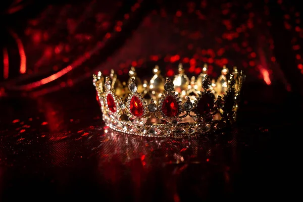 Luxury crown with ruby gemstones on red sparkle background