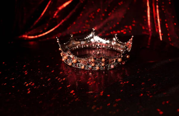Luxury crown with ruby gemstones on red sparkle background
