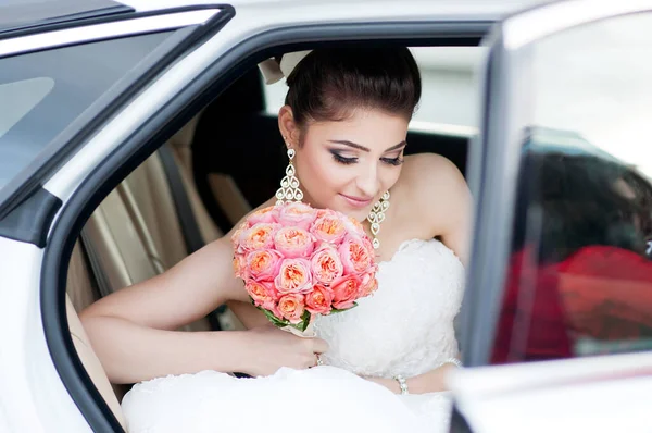 Portrait of happy positive bride. Sits in the car. Wedding make up