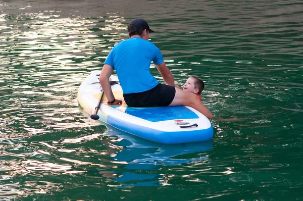 Dad and stand-up paddle board together. SUP board