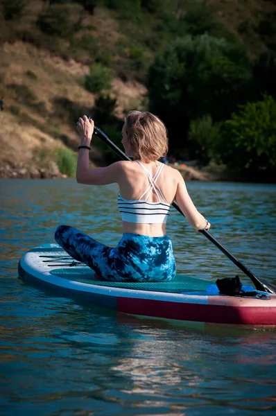 女の子は山の背景に川にSupボードに乗る — ストック写真
