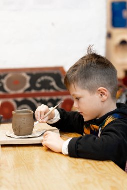 A boy creates a pot and decorating in a pottery workshop clipart