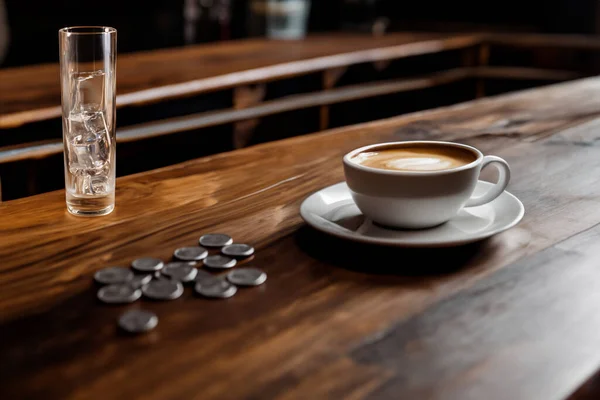 Coffee cup and glass of water on wooden table in coffee shop
