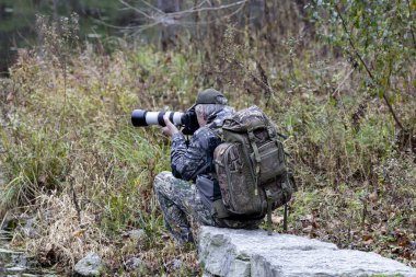 Kamuflaj kıyafetli vahşi yaşam fotoğrafçısı.