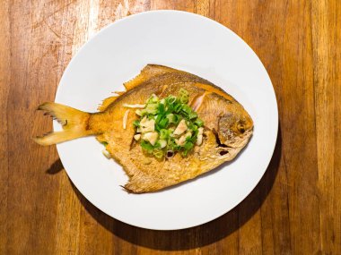 Tabakta yeşil soğan servis edilen geleneksel kızarmış deniz kabuğu balığı sosu..