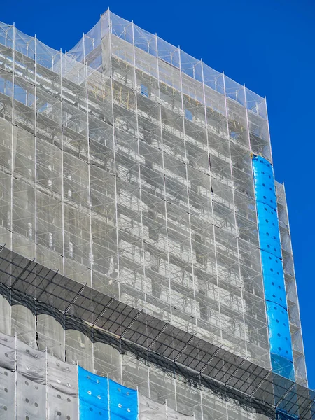正在建设中的大楼 包裹着蓝白相间的保护安全网 — 图库照片