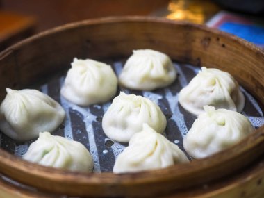 Steamed baozi dumplings stuffed with meat in a bamboo steamer.