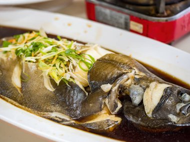 Soya soslu haşlanmış balık, beyaz tabakta servis edilir.