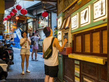 YENİ TAIPEI TAIWAN - 27 Ağustos 2024: Gezen ve alışveriş yapan turistlerle Jiufen eski caddesi. Geleneksel Çin fenerleri dar sokaklar boyunca asılı. Taipei yakınlarında popüler bir seyahat merkezidir..