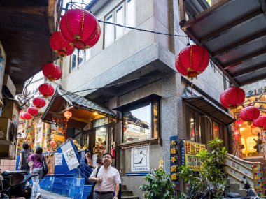 YENİ TAIPEI TAIWAN - 27 Ağustos 2024: Gezen ve alışveriş yapan turistlerle Jiufen eski caddesi. Geleneksel Çin fenerleri dar sokaklar boyunca asılı. Taipei yakınlarında popüler bir seyahat merkezidir..