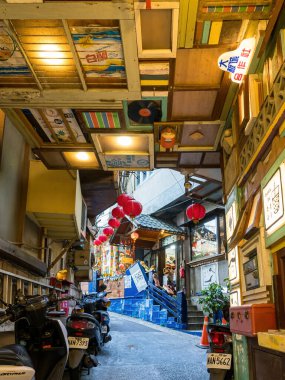 YENİ TAIPEI TAIWAN - 27 Ağustos 2024: Gezen ve alışveriş yapan turistlerle Jiufen eski caddesi. Geleneksel Çin fenerleri dar sokaklar boyunca asılı. Taipei yakınlarında popüler bir seyahat merkezidir..