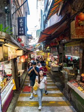 YENİ TAIPEI TAIWAN - 27 Ağustos 2024: Gezen ve alışveriş yapan turistlerle Jiufen eski caddesi. Geleneksel Çin fenerleri dar sokaklar boyunca asılı. Taipei yakınlarında popüler bir seyahat merkezidir..