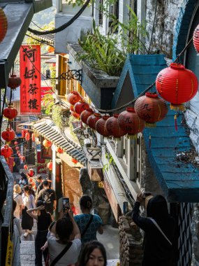 YENİ TAIPEI TAIWAN - 27 Ağustos 2024: Gezen ve alışveriş yapan turistlerle Jiufen eski caddesi. Geleneksel Çin fenerleri dar sokaklar boyunca asılı. Taipei yakınlarında popüler bir seyahat merkezidir..
