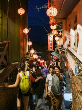 YENİ TAIPEI TAIWAN - 27 Ağustos 2024: Gezen ve alışveriş yapan turistlerle Jiufen eski caddesi. Geleneksel Çin fenerleri dar sokaklar boyunca asılı. Taipei yakınlarında popüler bir seyahat merkezidir..