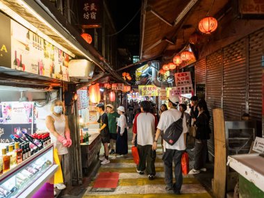 YENİ TAIPEI TAIWAN - 27 Ağustos 2024: Gezen ve alışveriş yapan turistlerle Jiufen eski caddesi. Geleneksel Çin fenerleri dar sokaklar boyunca asılı. Taipei yakınlarında popüler bir seyahat merkezidir..
