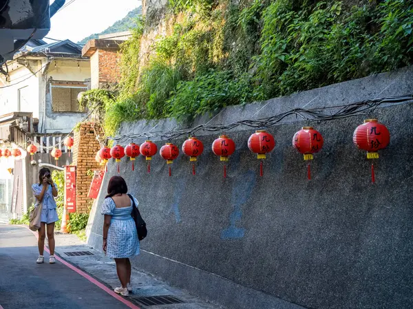 YENİ TAIPEI TAIWAN - 27 Ağustos 2024: Gezen ve alışveriş yapan turistlerle Jiufen eski caddesi. Geleneksel Çin fenerleri dar sokaklar boyunca asılı. Taipei yakınlarında popüler bir seyahat merkezidir..