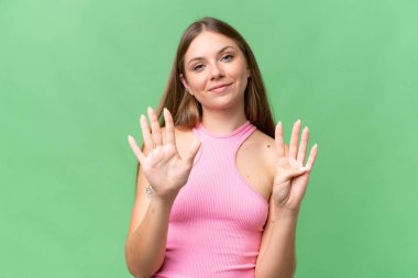 Genç, güzel, sarışın bir kadın izole edilmiş arka planda dokuz parmaklı sayıyor.