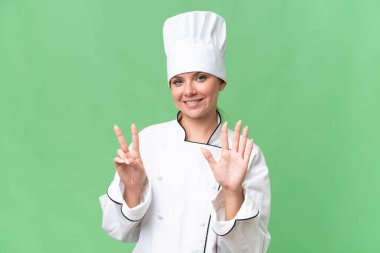 Genç aşçı kadın izole edilmiş yeşil arka plan 