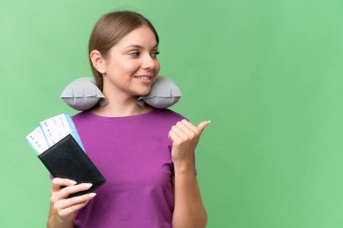 Şişirilebilir seyahat yastığı ile genç, güzel sarışın kadın izole arka planda bir ürün sunmak için kenarı işaret ediyor.