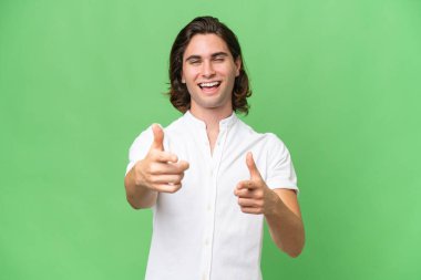 Yeşil krom arka planda izole edilmiş genç beyaz adam öne bakıyor ve gülümsüyor.