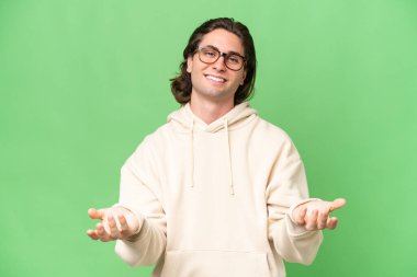 Yeşil krom arka planda izole edilmiş genç beyaz adam mutlu ve gülümsüyor.