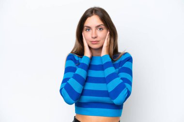 Beyaz arka planda izole edilmiş genç beyaz kadın hayal kırıklığına uğramış ve kulaklarını kapatmış.